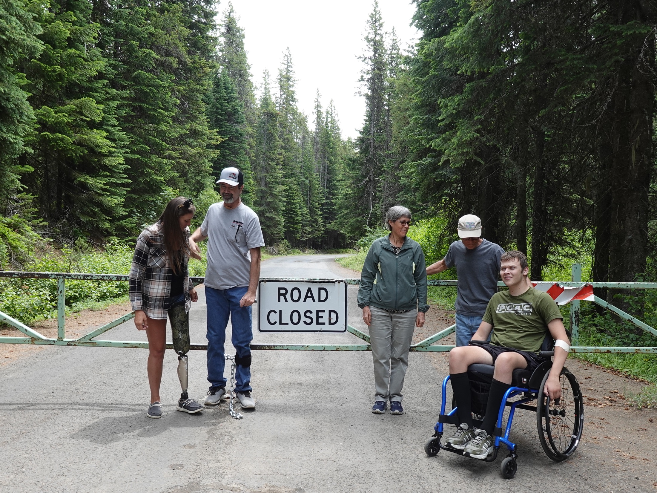 A group of people with and without disabilities at a closed forest road